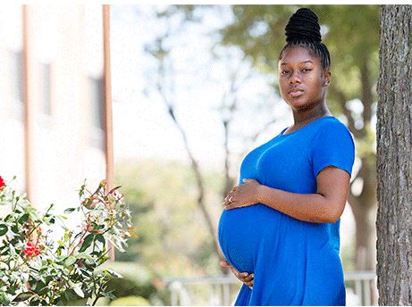 A pregnant black woman standing outside 