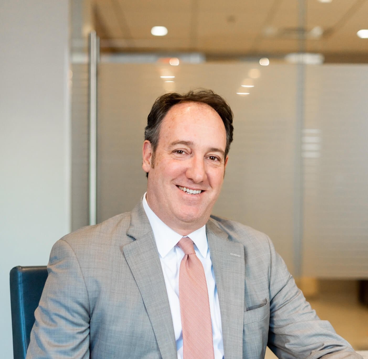 Whitney Lester posing for a professional headshot, wearing a suit and tie.