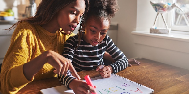 A mother showing her daughter how to write the alphabet