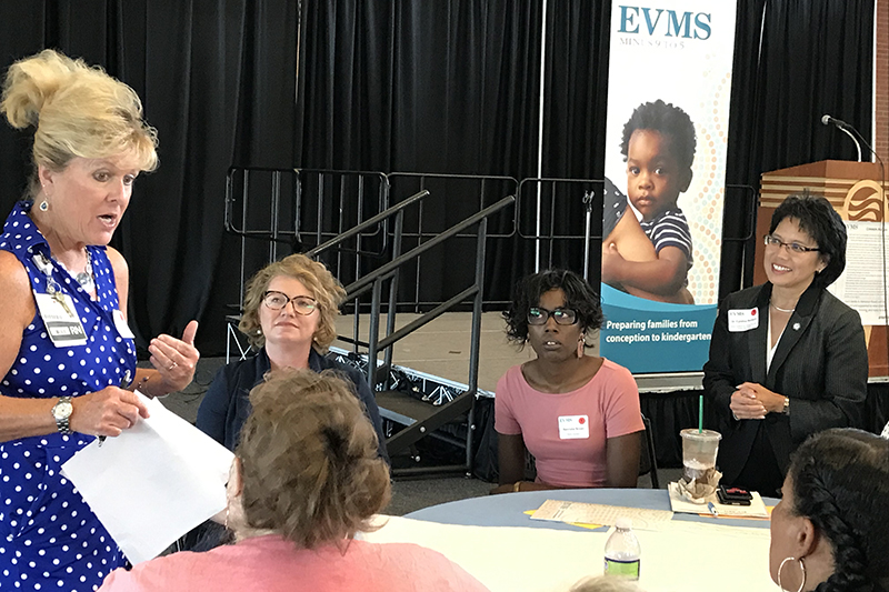 Members of a Minus 9 to 5 work group talk at a table