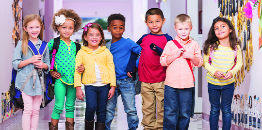 Diverse group of kindergarten students stand in a hallway