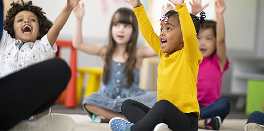 Diverse group of preschool children raising their hands	