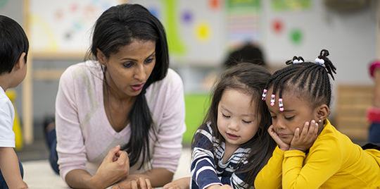 Diverse group of preschool children raising their hands	