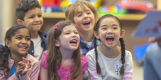 Diverse group of preschool children raising their hands	