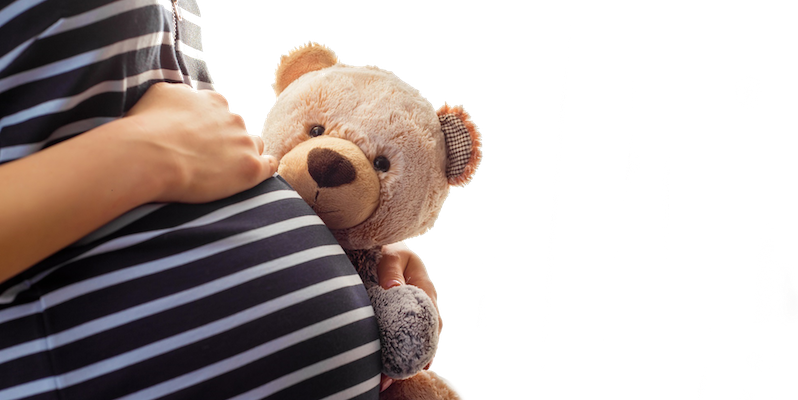 Pregnant woman holding teddy bear