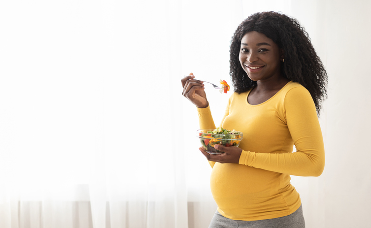 Smiling pregnant women eating a salad