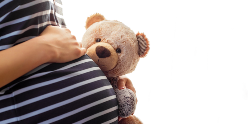 Pregnant girl holding teddy bear