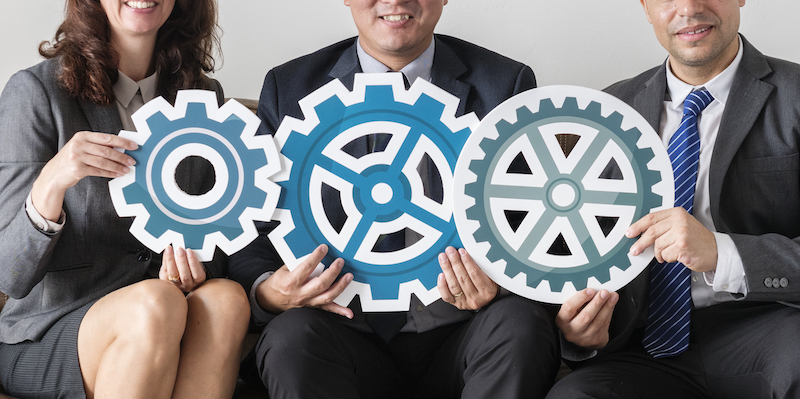 Image of business men and woman holding gears